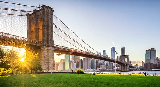 View of Brooklyn Bridge and Lower Manhattan at sunset with sun Flare and a blank space