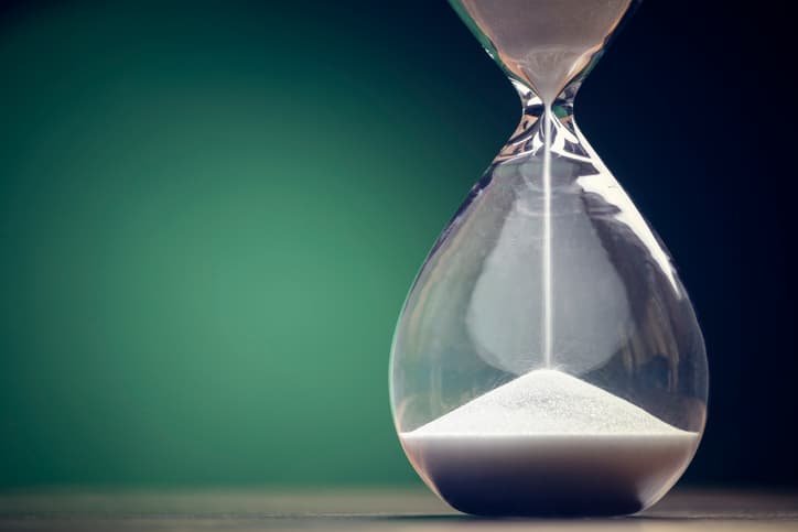 Image of an hourglass running against a green background