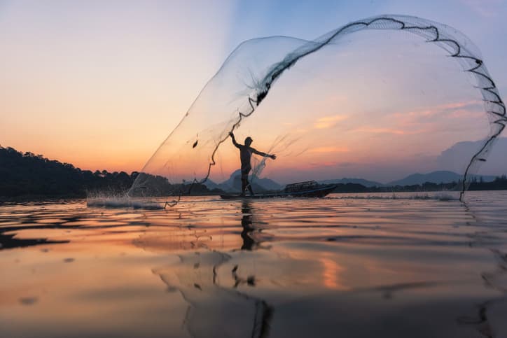 A fisherman casts a net across the water.