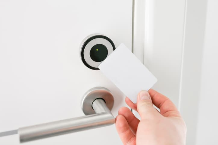 Hotel door - Young man holding a keycard in front of the electronic sensor of a room door.