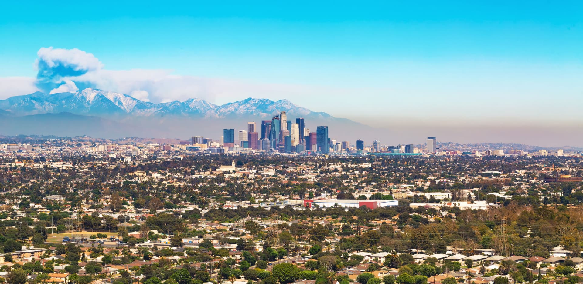 View of Los Angeles with smoke from a forest fire rising from the mountains behind