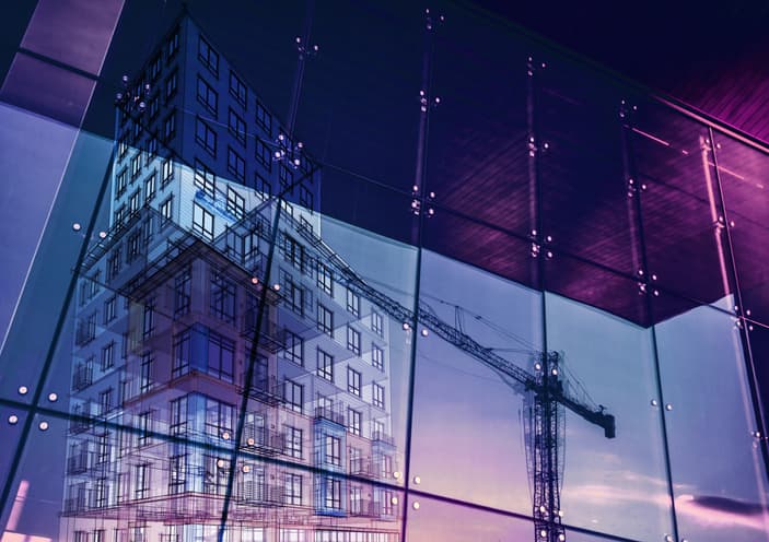 Construction crane and a new high rise building reflected into a newly built office building. New offices are being built to satisfy the growing demand