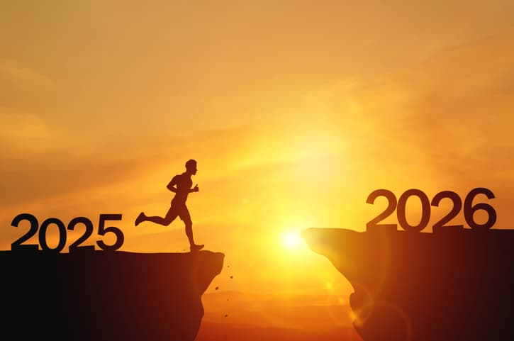 New Year 2026, Inspiration and progress towards new success. Silhouettes of human jumping over cliff towards finish line with text new year 2026 on sunset beautiful
