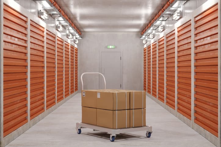 Self Storage Units And Close-up Of Hand Truck With Cardboard Boxes In Corridor