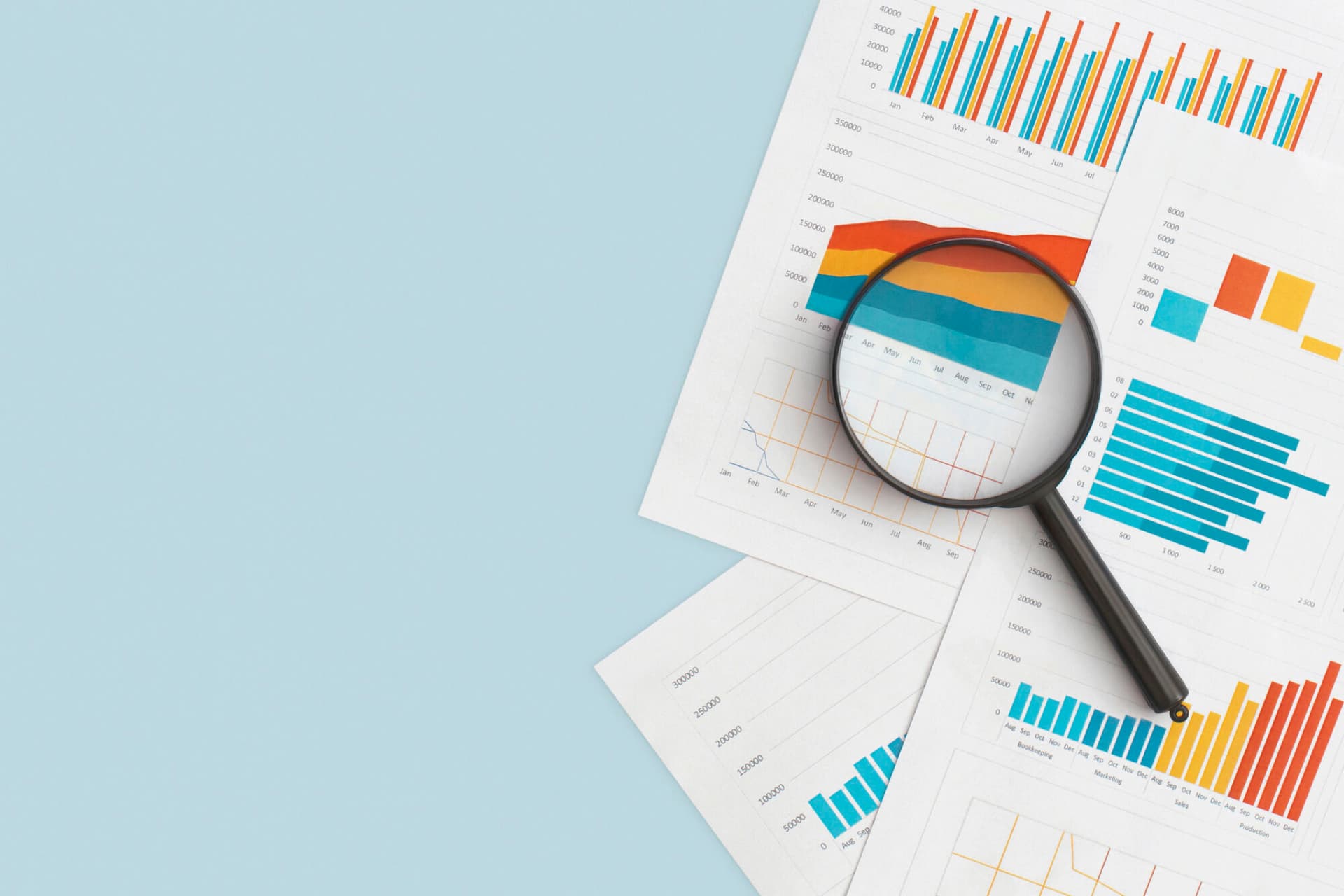 Business graphs, charts and magnifying glass on table