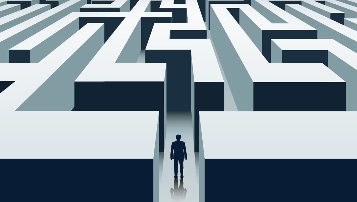 A man stands at the entrance of a maze.