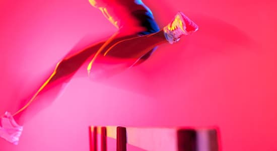 A female athlete jumps over a hurdle