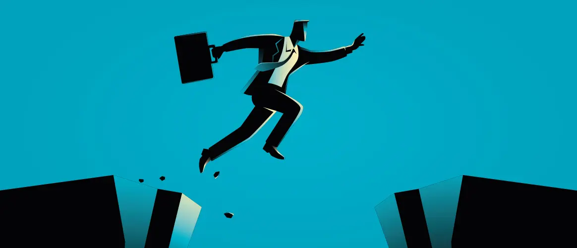 A businessman jumps from a crumbling cliff onto a safe cliff