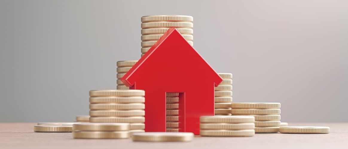 Image of a block house next to stacks of coins.