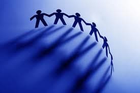 Photo of paper cutouts of the outlines of people connected in a half circle, representing the world and social impact.