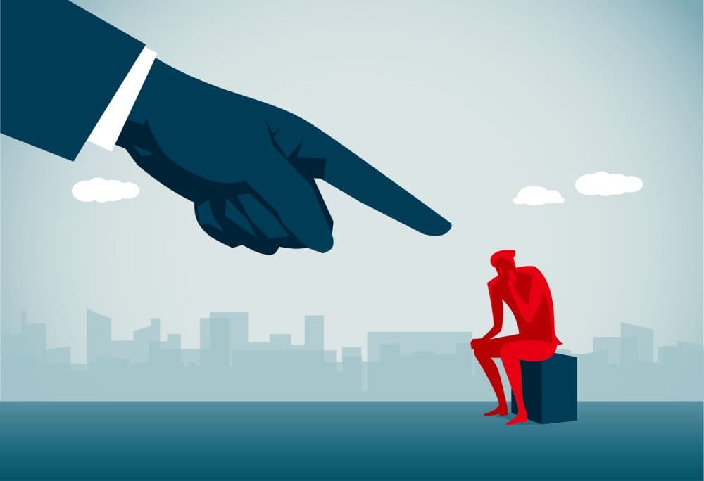 Photo of illustration of giant finger blaming person who is sitting.