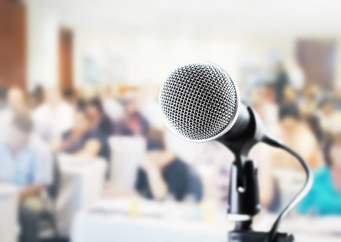 Dynamic microphone in front of a seminar room, with people waiting in anticipation for a speech.