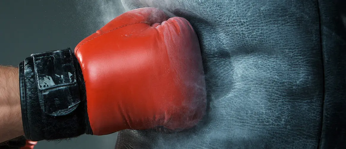 A boxing glove punches a punching bag