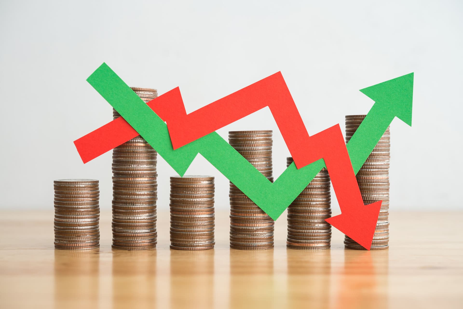 Stacks of coins with red and green graph arrows on top.