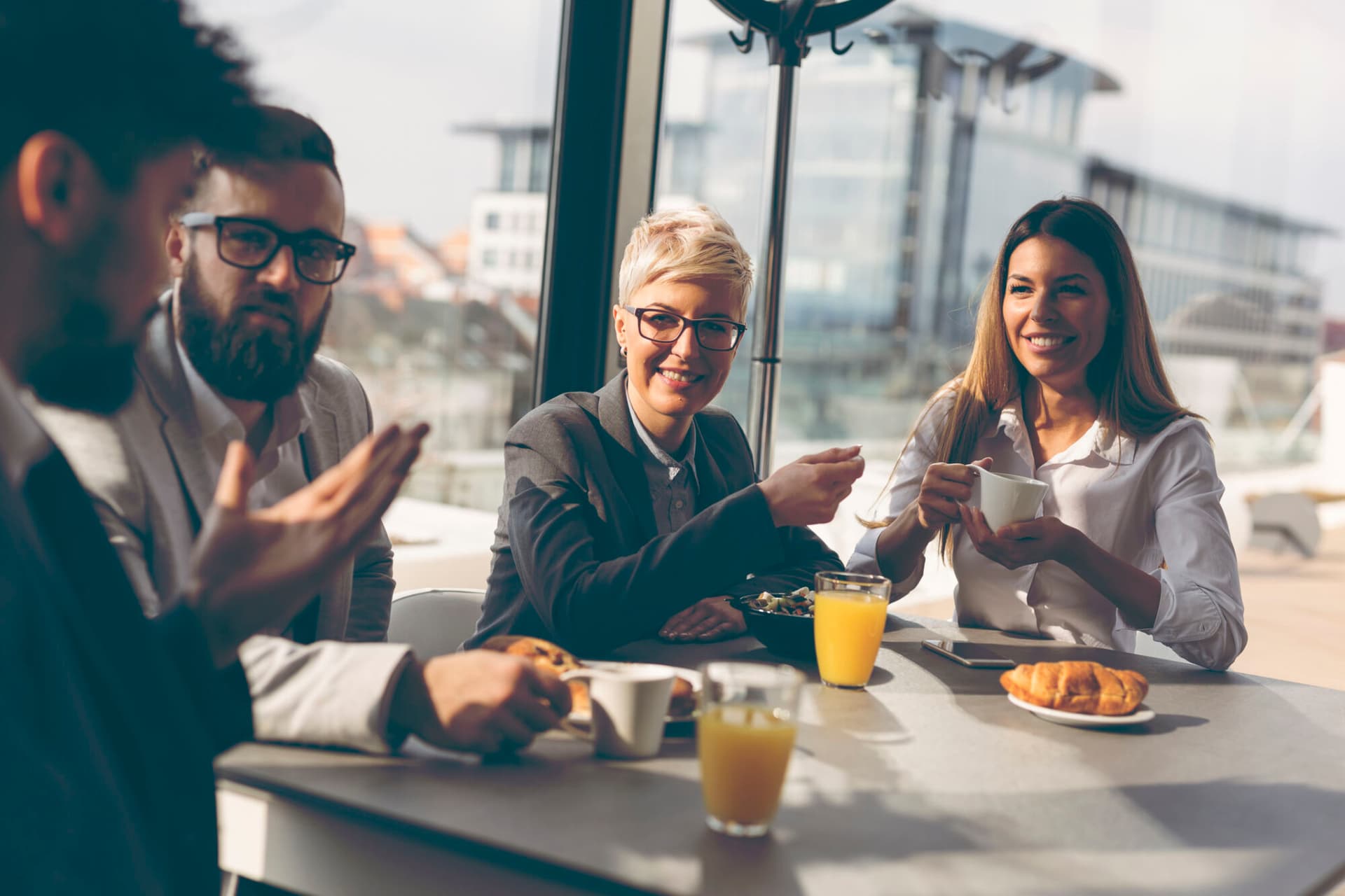 Group of business people having breakfast in company's restaurant. Focus on the women