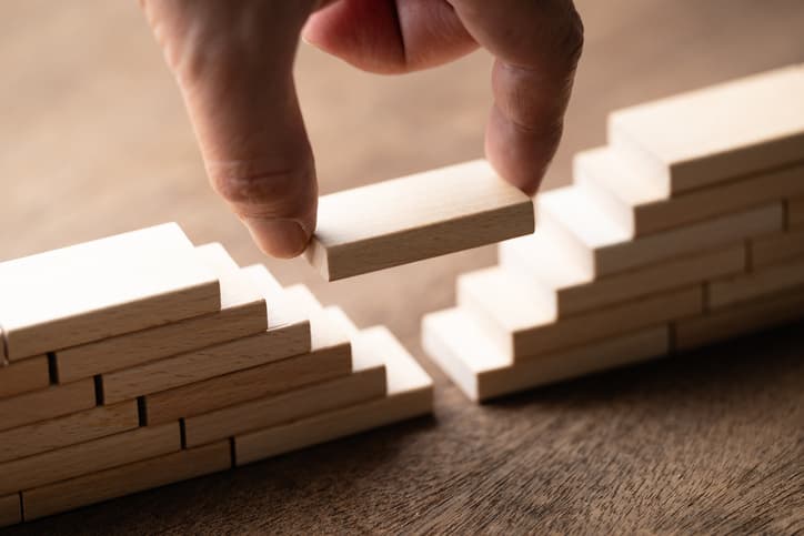 A hand places a block in between a gap of stacked blocks
