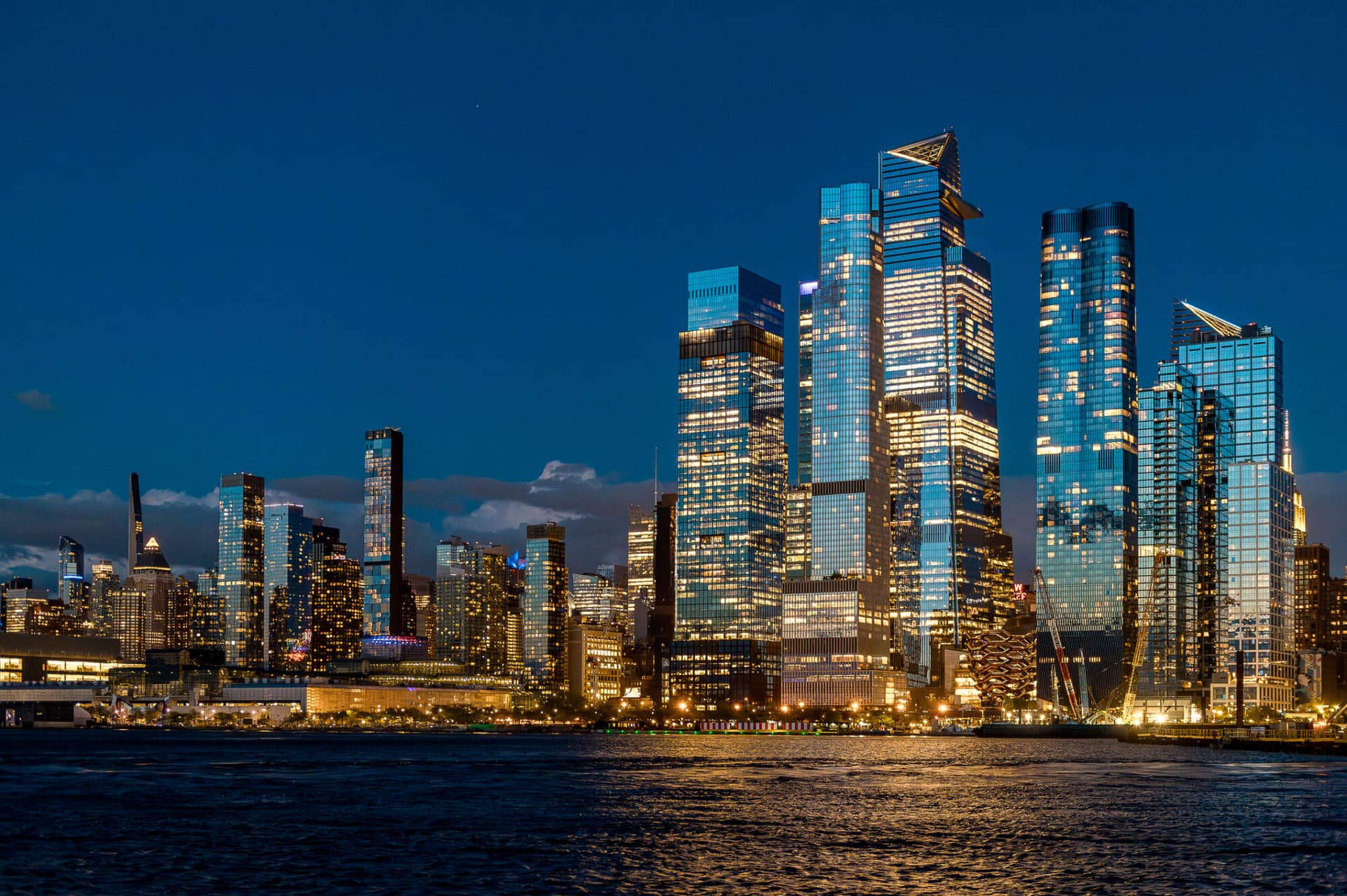 Wide view of Hudson Yards skyline and Vessel at night. Panoramic night shot of Manhattan west side with illuminated Vessel and Hudson Yards modern skyscrapers.