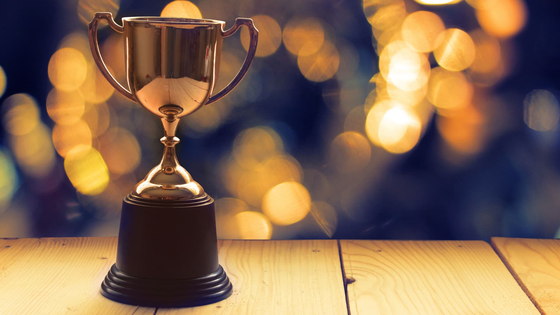 Win prize trophy award on wood table with background window.